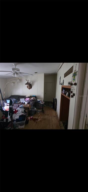 A cluttered living room features wood-look flooring, a ceiling fan, and a mounted deer head — 210 SANTA ROSA ROAD, CANTONMENT, FL