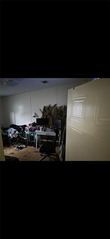 A bedroom features a white desk, a black office chair, and a cluttered side table — 210 SANTA ROSA ROAD, CANTONMENT, FL