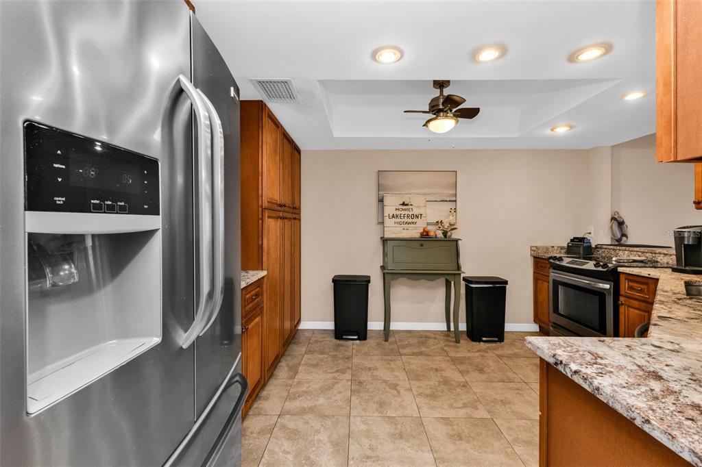 A kitchen features stainless steel appliances, wood cabinetry, granite countertops, and tile flooring — 9050 MIDNIGHT PASS ROAD UNIT 1, SARASOTA, FL