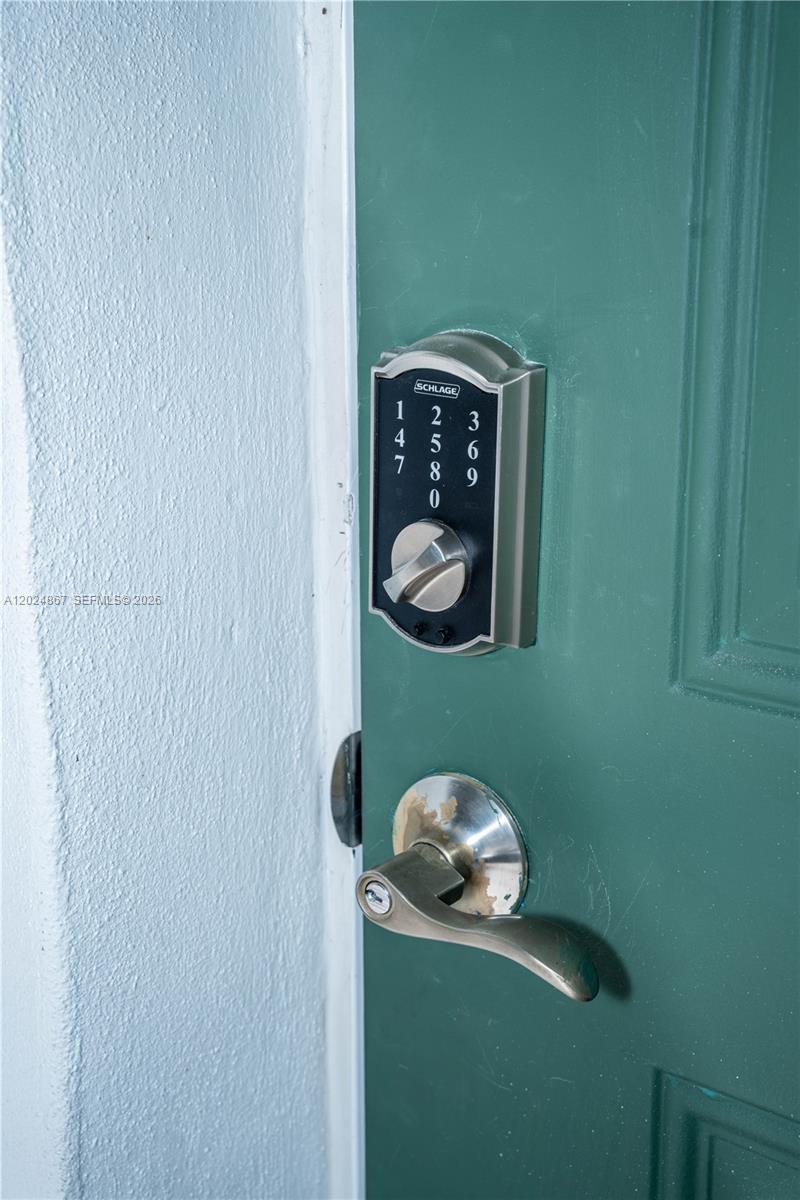A Schlage electronic keypad deadbolt and a metal lever handle are mounted on a green door — 247 NW 58th St, Miami FL 33127, MIAMI, FL