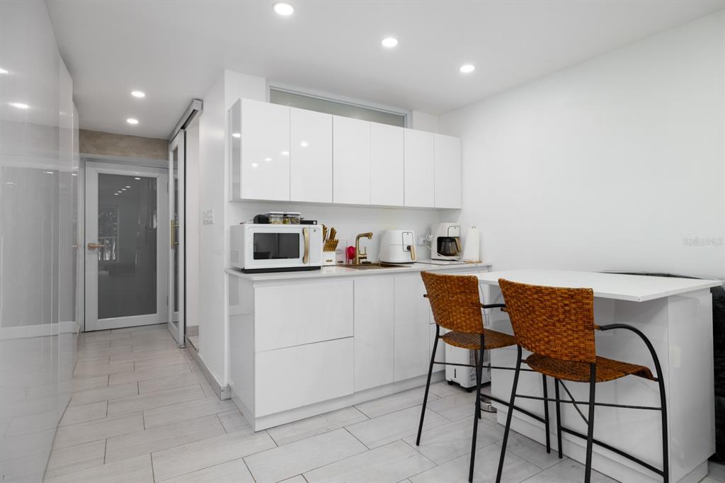 A modern kitchen features white glossy cabinets, a central island, and a gold-toned sink faucet — 4633 AV. ISLA VERDE UNIT 105, CAROLINA, PR