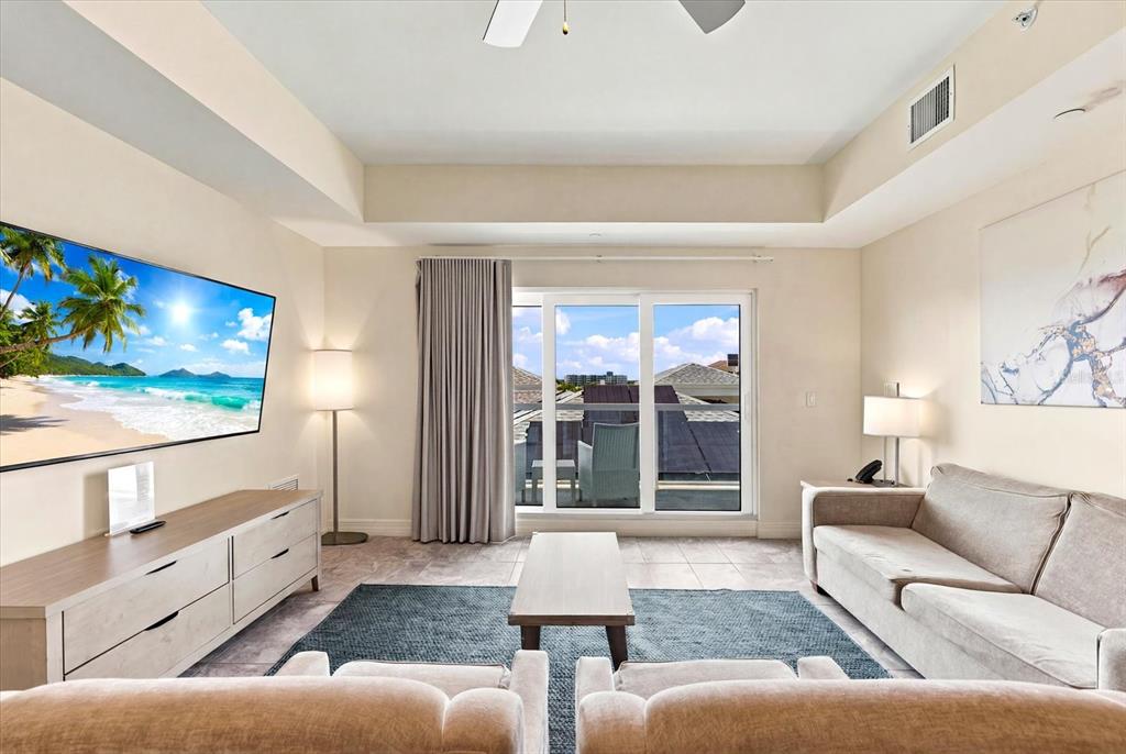 A dining area with a wooden table and chairs opens into a living room space — 24 AVALON STREET UNIT 405, CLEARWATER BEACH, FL