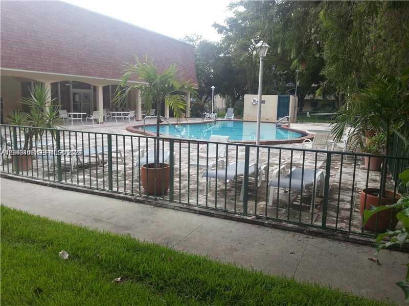 A fenced outdoor swimming pool area with lounge chairs and a covered patio building — 500 NE 2nd St # 408, Dania Beach FL 33004, DANIA BEACH, FL
