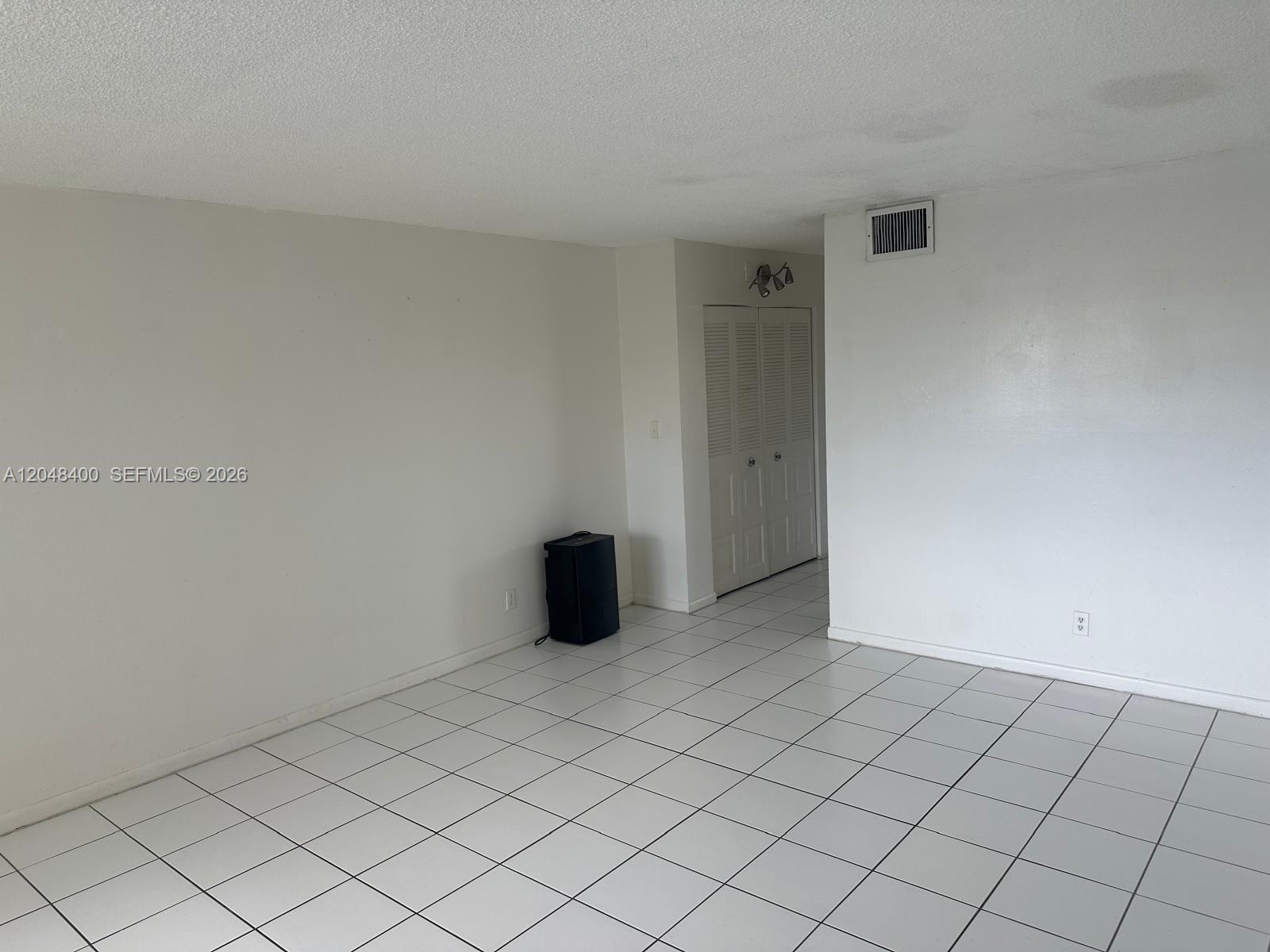 An empty room features white walls, white tiled flooring, and a set of louvered closet doors — 500 NE 2nd St # 408, Dania Beach FL 33004, DANIA BEACH, FL