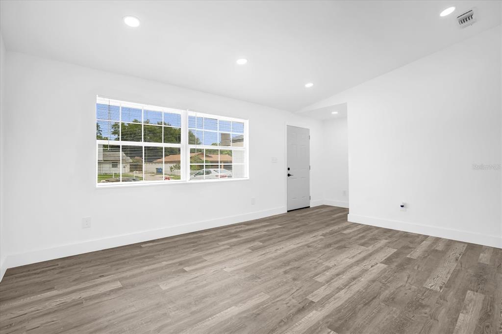 An empty room features white walls, recessed lighting, and light-colored wood-look plank flooring — 1730 AVENUE C NE, WINTER HAVEN, FL