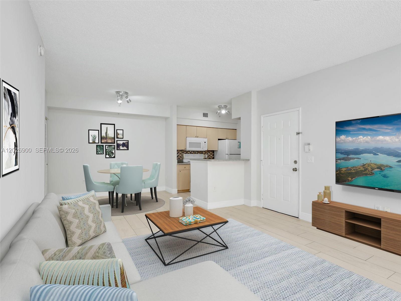 An open-concept living and dining area features light-colored tile floors and a modern kitchen — 1235 Reserve Way # 107, Naples FL 34105, NAPLES, FL