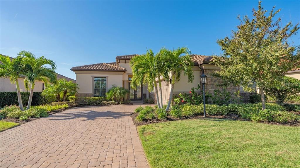 A single-story house with a paved driveway, palm trees, and stone accents on the exterior — 4714 CABREO COURT, BRADENTON, FL