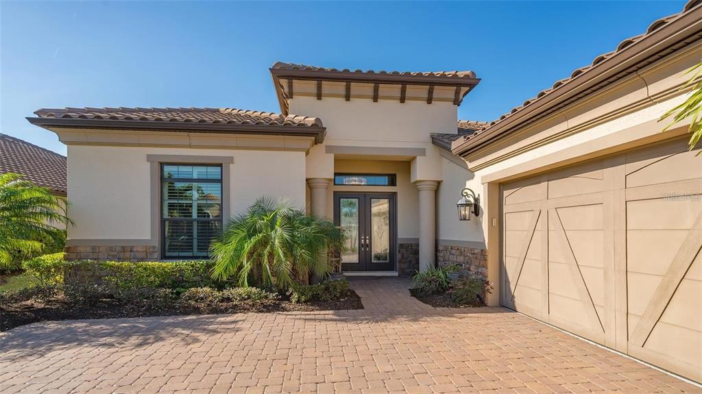 A single-story house with a beige stucco exterior, stone accents, and a paved driveway — 4714 CABREO COURT, BRADENTON, FL
