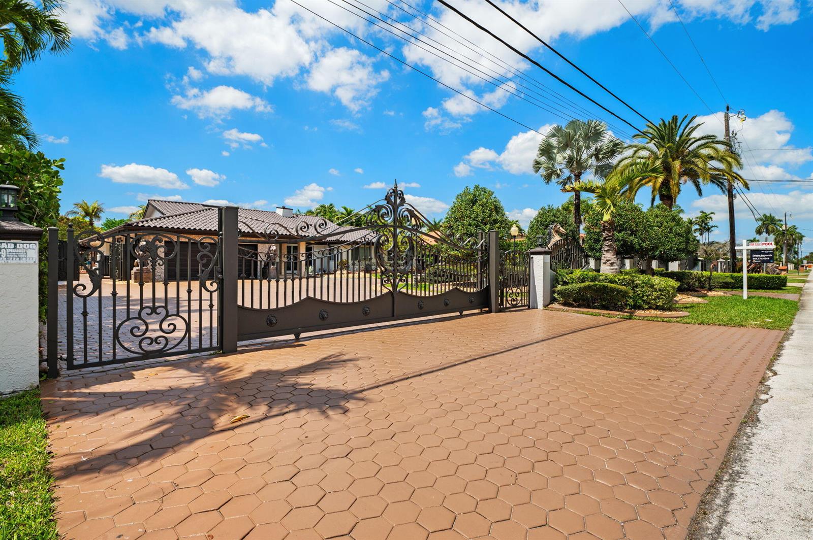 A gated driveway leads to a house with a tiled roof and palm trees — 2840 SW 128th Avenue, Miami FL 33175, MIAMI, FL