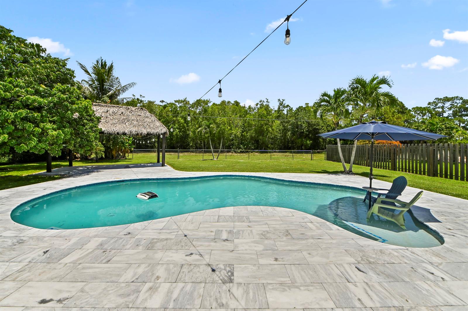 A backyard features a swimming pool with a tanning ledge, patio, and a tiki hut — 7635 Oakmont Drive, Lake Worth FL 33467, LAKE WORTH, FL