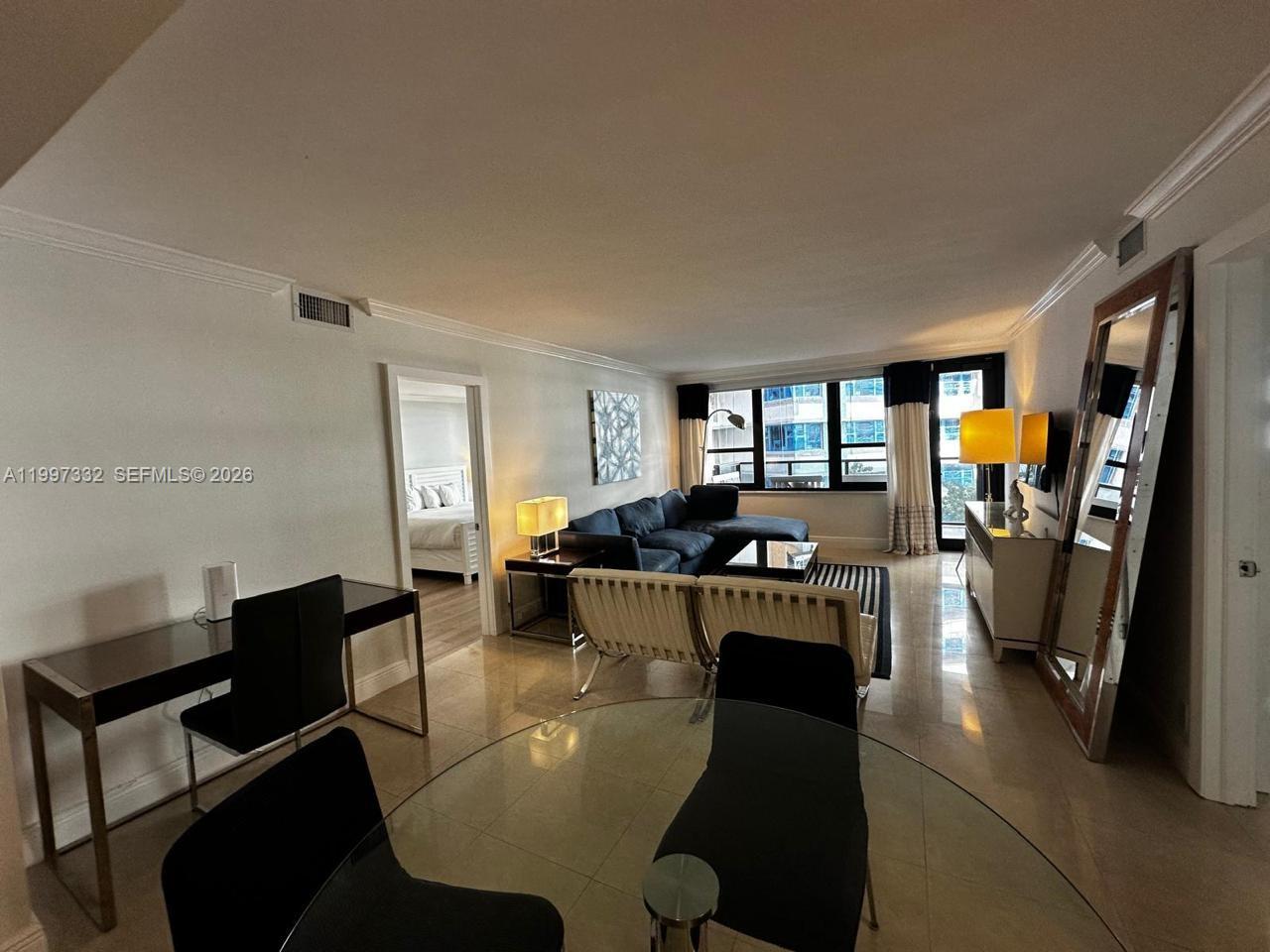 A living room and dining area feature tile floors, a large mirror, and balcony access — 5225 Collins Ave # 614, Miami Beach FL 33140, MIAMI BEACH, FL