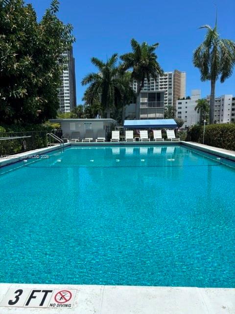A swimming pool with lounge chairs and palm trees in front of apartment buildings — 3177 S Ocean Dr # 217, Hallandale Beach FL 33009, HALLANDALE BEACH, FL