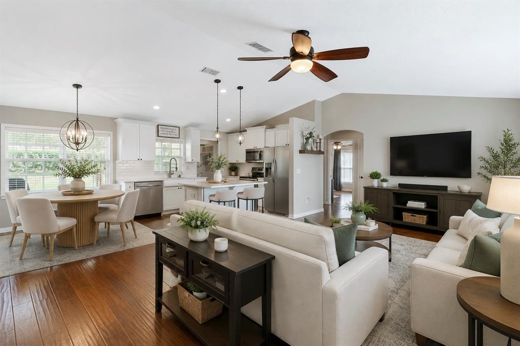 An open-concept living room and kitchen feature hardwood floors, white cabinetry, and neutral furniture — 64 E CREST AVENUE, WINTER GARDEN, FL