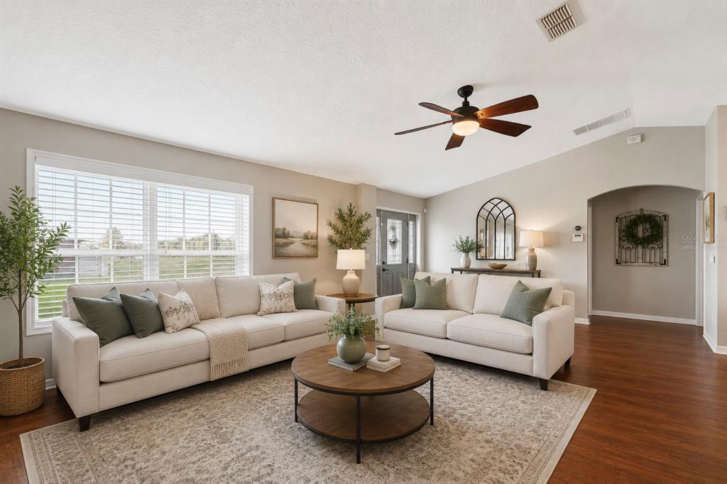 A living room features two beige sofas, a round wooden coffee table, and hardwood floors — 64 E CREST AVENUE, WINTER GARDEN, FL