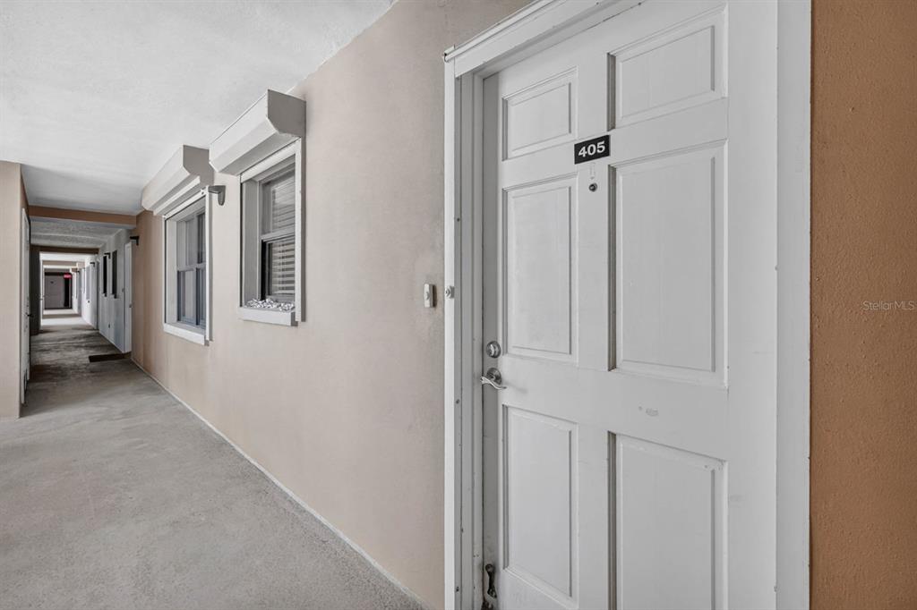 A white door labeled 405 opens onto a concrete outdoor hallway with windows — 4745 S ATLANTIC AVENUE UNIT 4050, PONCE INLET, FL