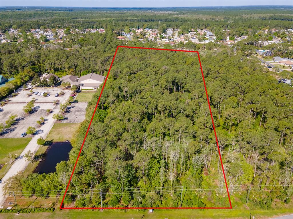 An aerial view shows a rectangular, wooded plot of land outlined in red — XXXX PINE LAKES PARKWAY, PALM COAST, FL
