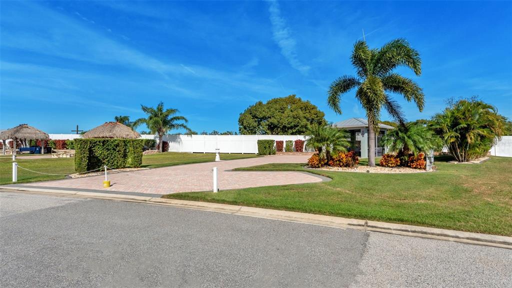 A paved driveway leads to a small structure with a thatched roof and palm trees — 2947 WOOD DUCK DRIVE, POLK CITY, FL