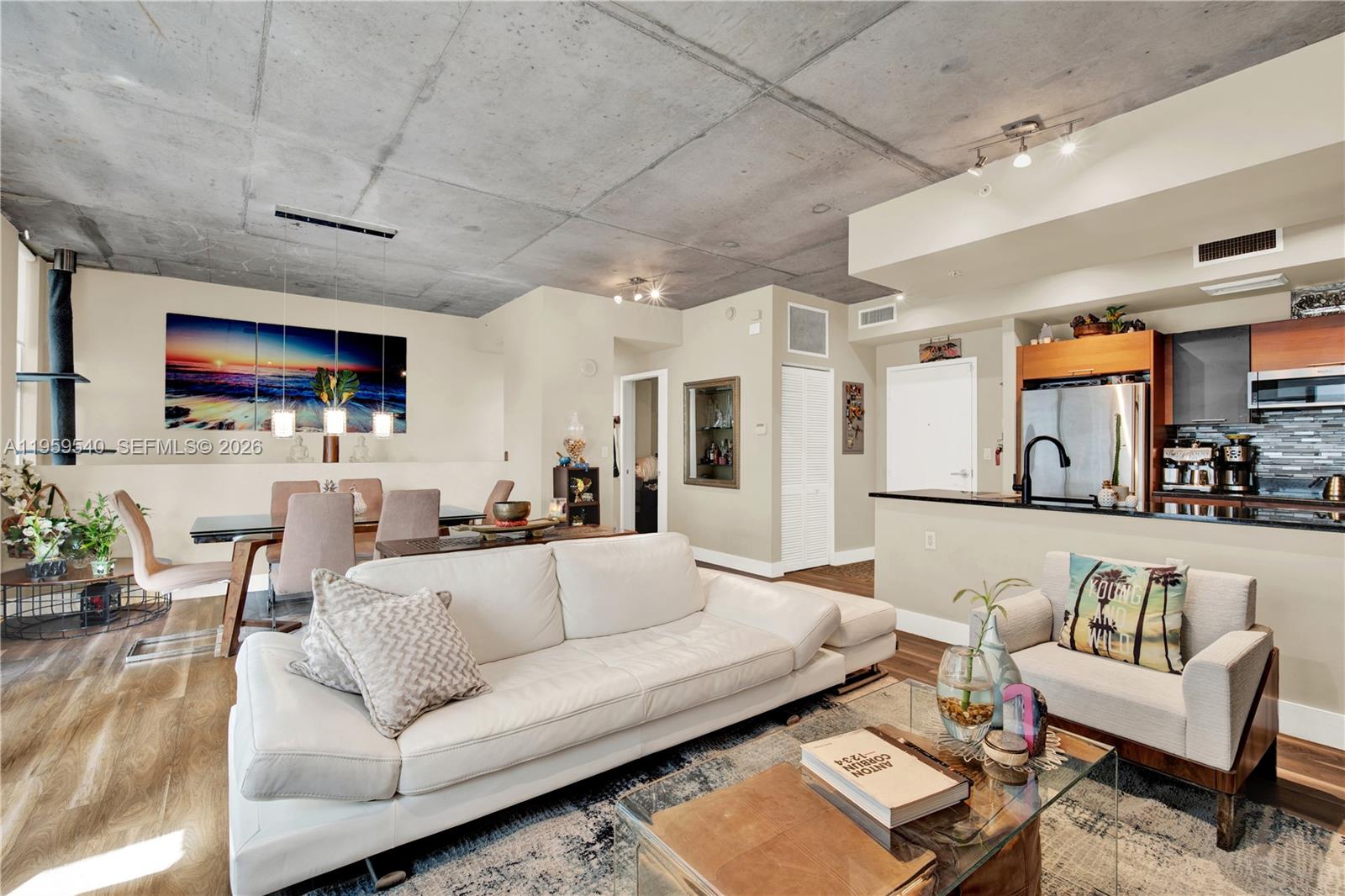 An open-concept living and dining area features a concrete ceiling and modern kitchen cabinetry — 3449 NE 1st Ave # 110, Miami FL 33137, MIAMI, FL
