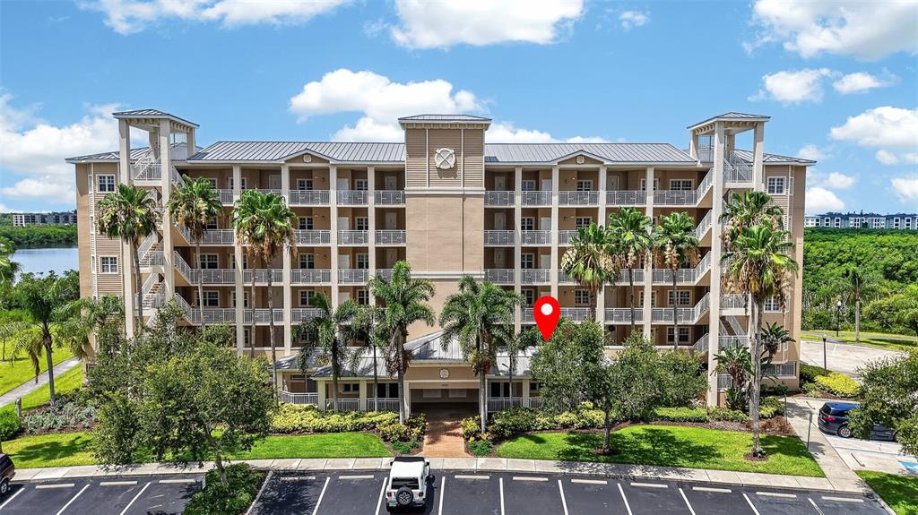 A multi-story beige apartment building with palm trees and a parking lot in front — 10002 KEY HAVEN ROAD UNIT 204, SEMINOLE, FL