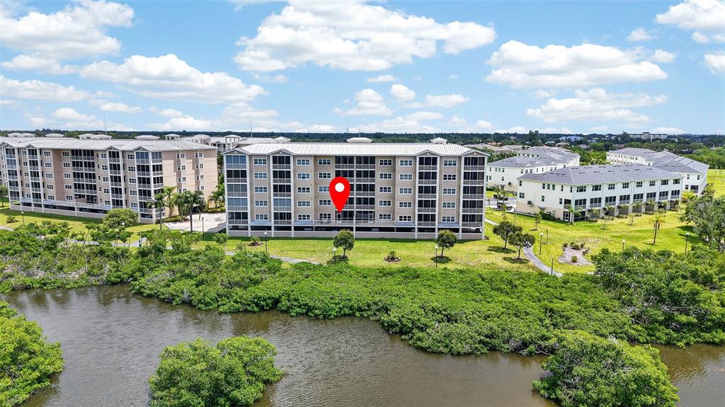 An aerial view shows a multi-story apartment building situated near a body of water — 10002 KEY HAVEN ROAD UNIT 204, SEMINOLE, FL