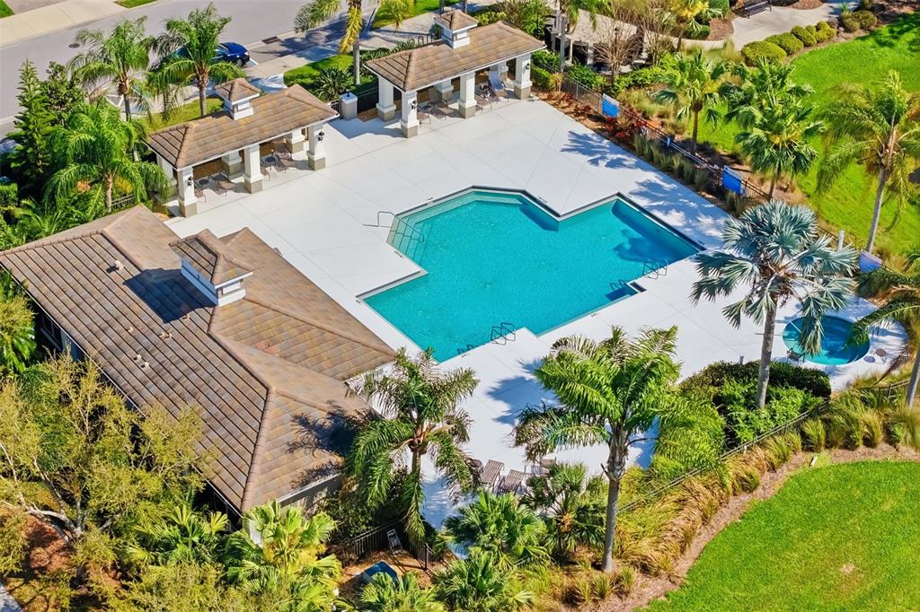 An aerial view shows a community swimming pool and spa with two covered pavilions — 5437 CHATHAM SQUARE WAY, BRADENTON, FL