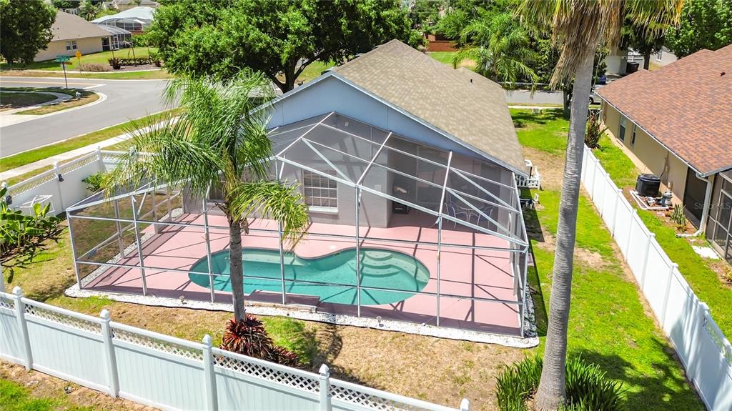 An aerial view of a house with a screened-in pool and a white vinyl fence — 7949 GOLDEN POND CIR, KISSIMMEE, FL