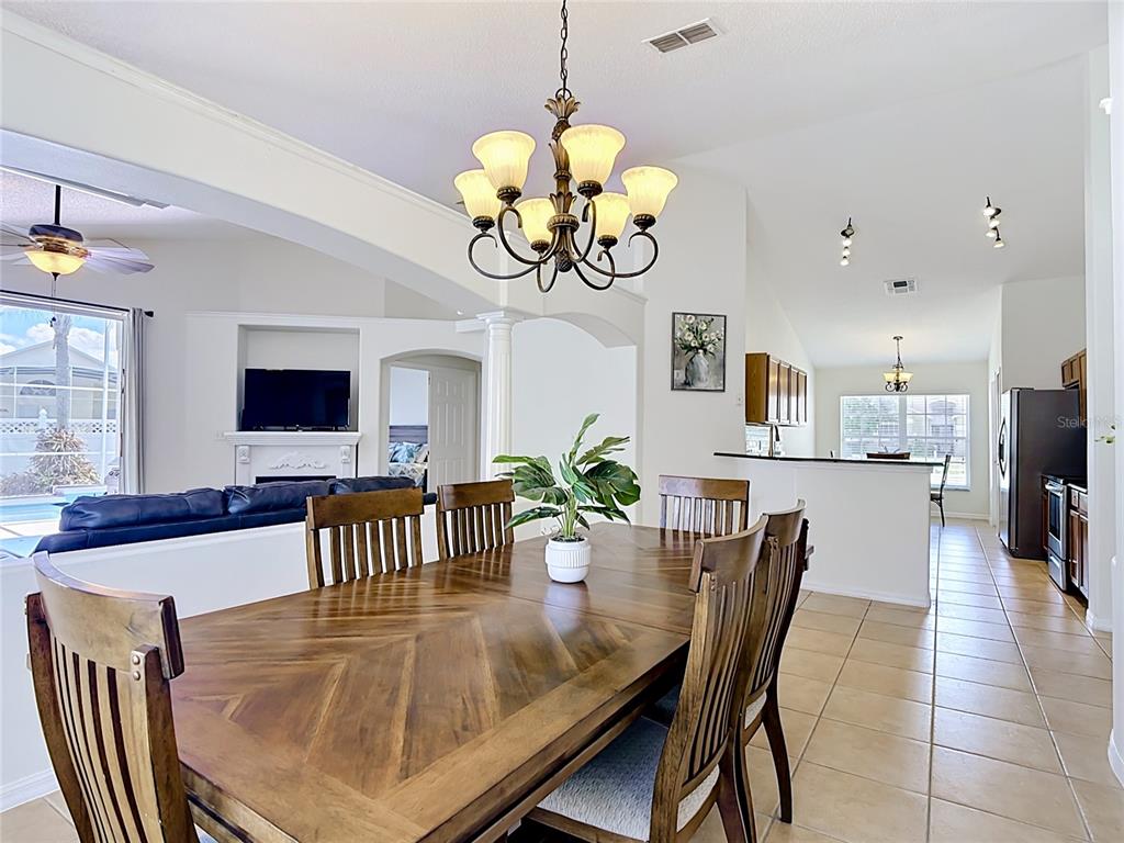A dining room with a wooden table, chandelier, and an open view of the kitchen — 7949 GOLDEN POND CIR, KISSIMMEE, FL
