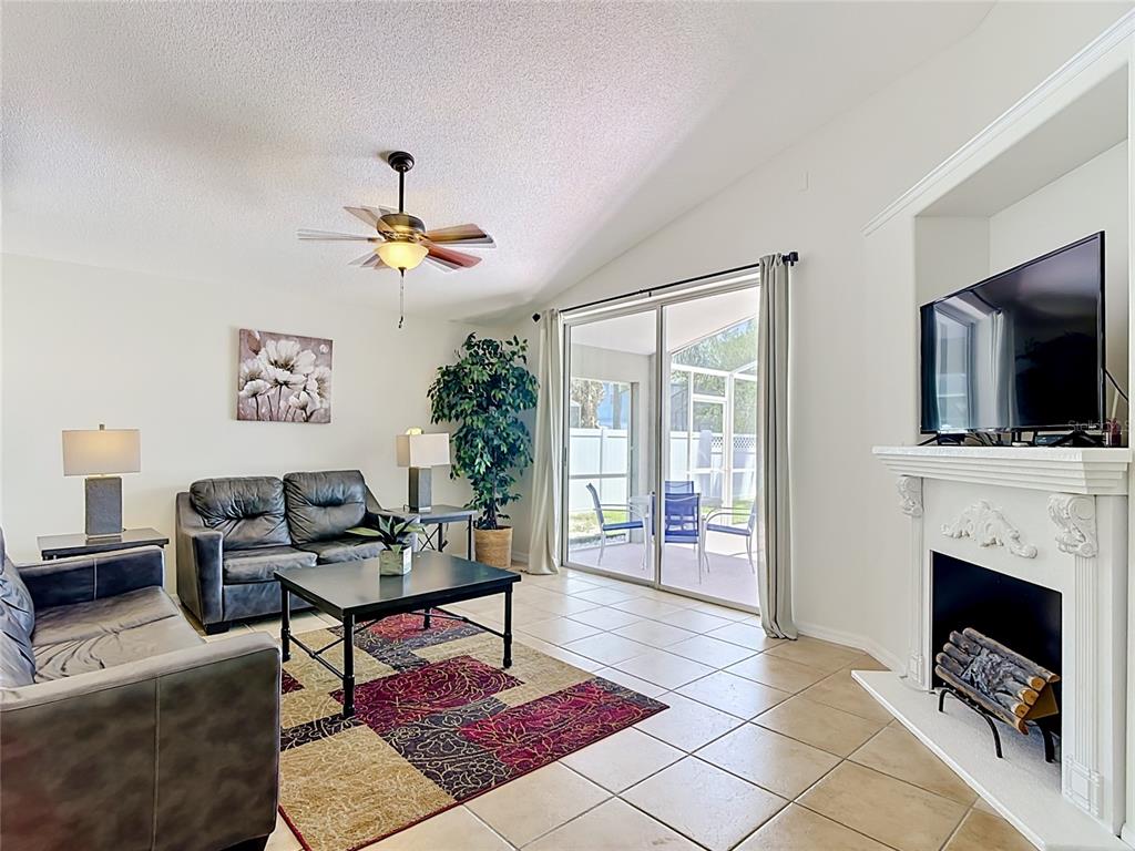 A living room features tile floors, a fireplace, a ceiling fan, and sliding glass doors — 7949 GOLDEN POND CIR, KISSIMMEE, FL