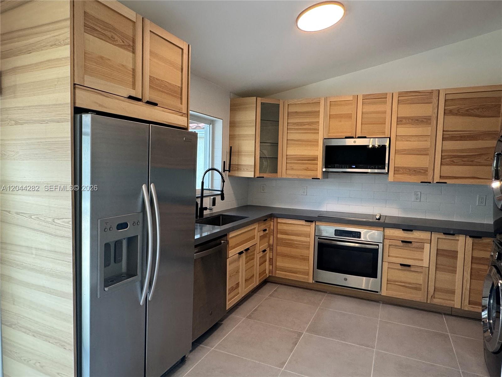 A kitchen features light wood cabinets, stainless steel appliances, and gray countertops — 12845 SW 150th Ter, Miami FL 33186, MIAMI, FL