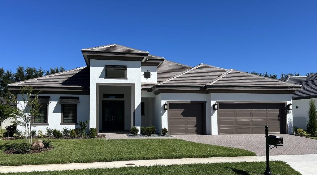 A single-story house with a white stucco exterior, a tiled roof, and a three-car garage — 180 JULIANA RIDGE WAY, AUBURNDALE, FL