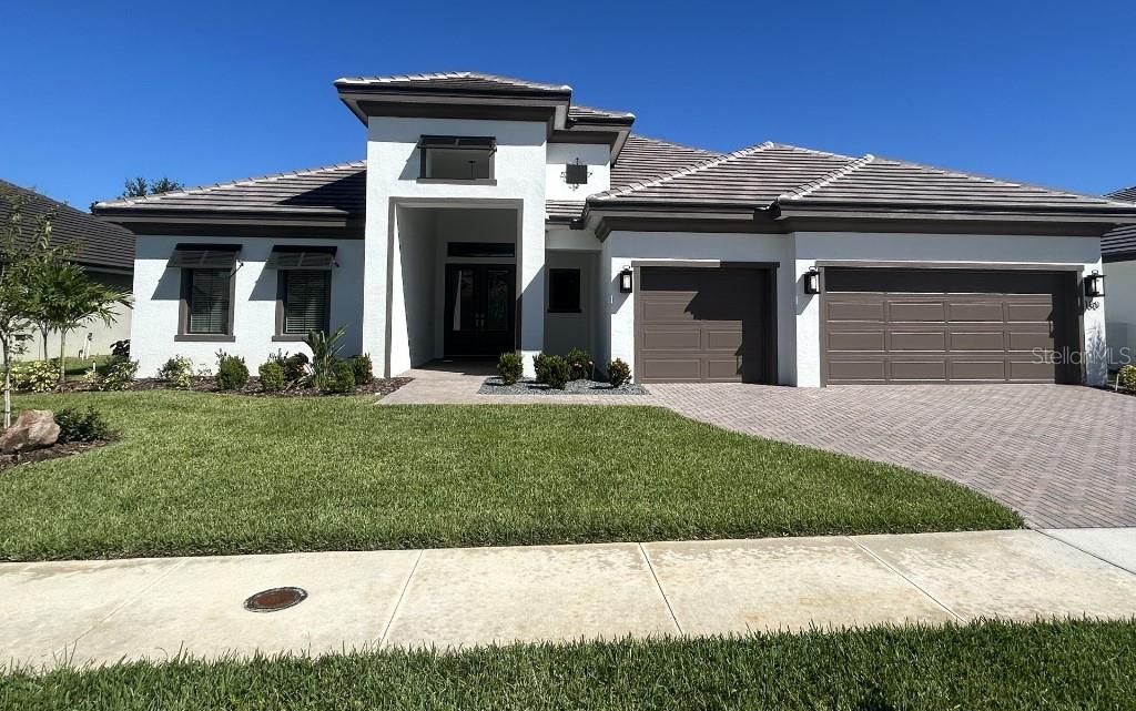 A single-story house with a white stucco exterior, a gray tile roof, and a three-car garage — 180 JULIANA RIDGE WAY, AUBURNDALE, FL