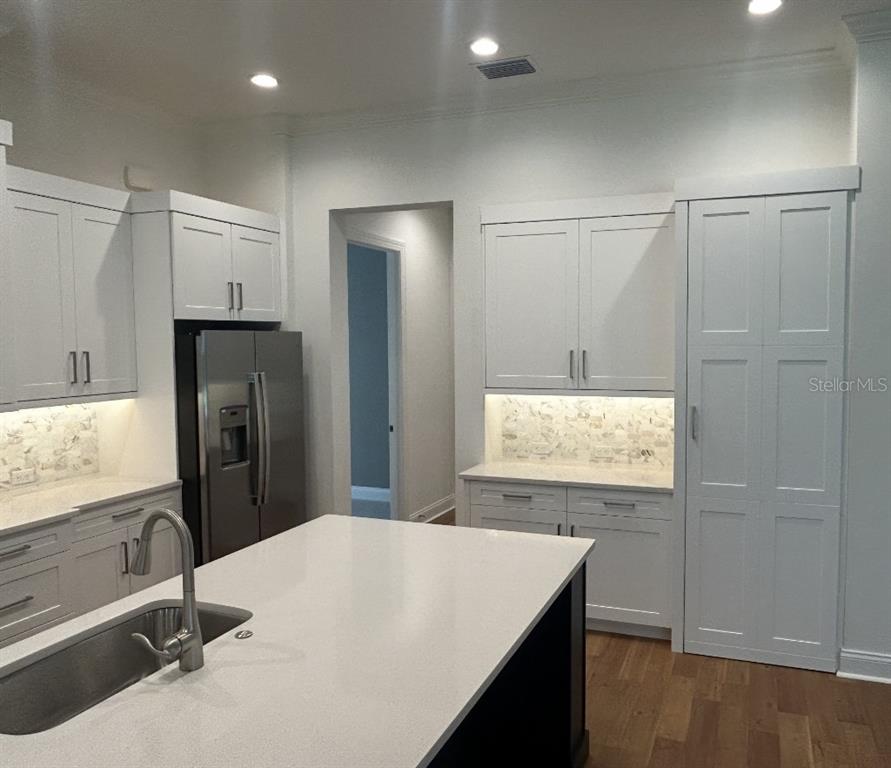 A modern kitchen features white cabinetry, a large island with a sink, and stainless steel appliances — 180 JULIANA RIDGE WAY, AUBURNDALE, FL