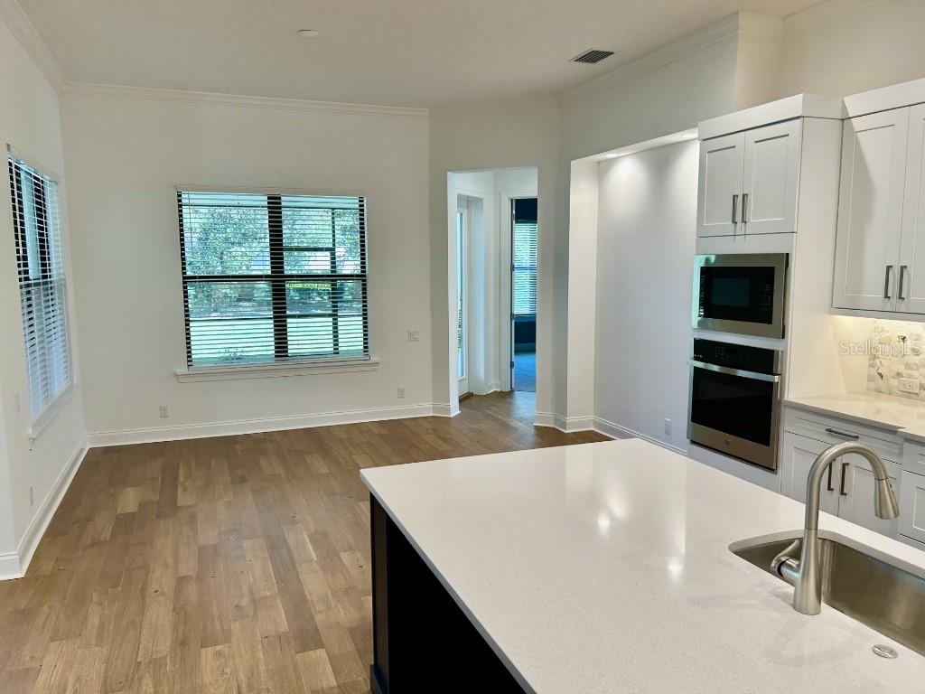A kitchen features a white island with a sink, stainless steel appliances, and wood flooring — 180 JULIANA RIDGE WAY, AUBURNDALE, FL