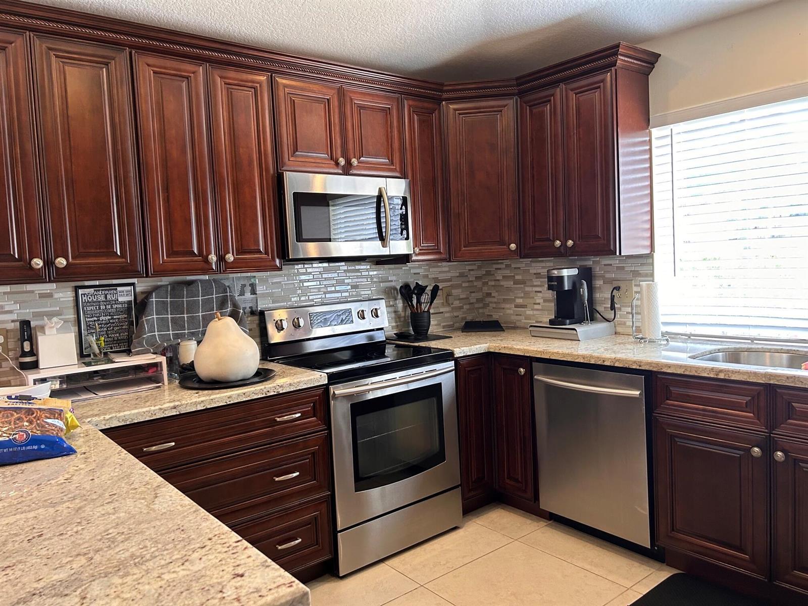 A kitchen featuring dark wood cabinets, stainless steel appliances, and granite countertops — 6754 Via Regina, Boca Raton FL 33433, BOCA RATON, FL