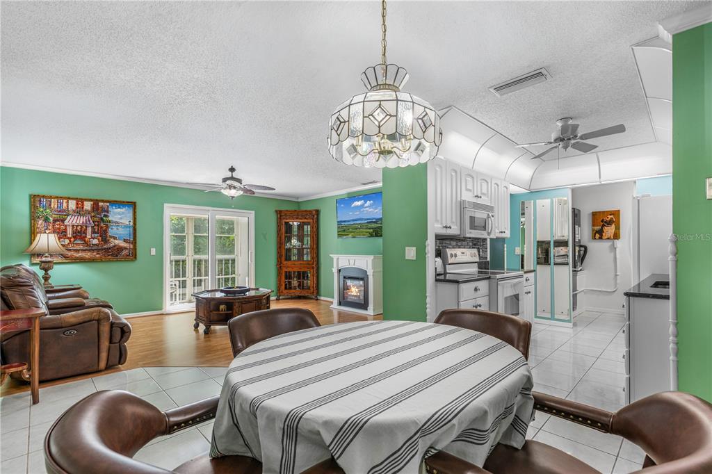 A dining area with a round table opens into a living room with green walls — 101 BENT TREE DRIVE UNIT 15, DAYTONA BEACH, FL