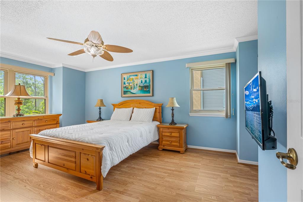 A bedroom with light blue walls, wood furniture, a ceiling fan, and wood-look flooring — 101 BENT TREE DRIVE UNIT 15, DAYTONA BEACH, FL