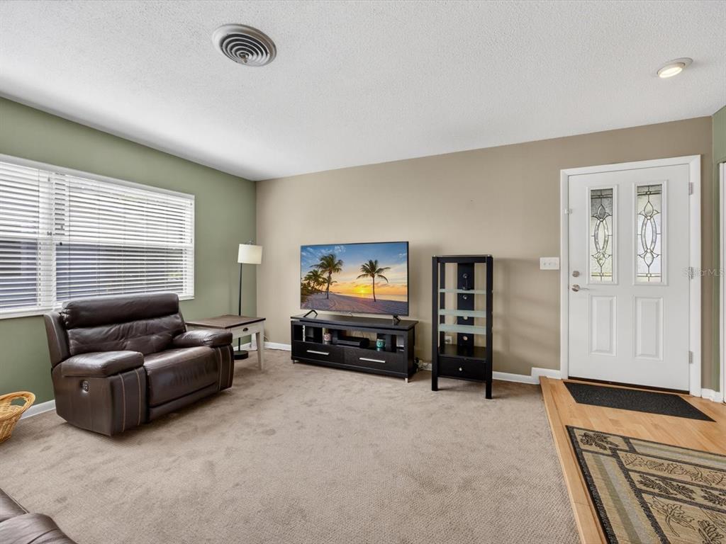 A living room features beige carpet, a brown leather recliner, a television, and a front door — 2803 BANCHORY ROAD, WINTER PARK, FL