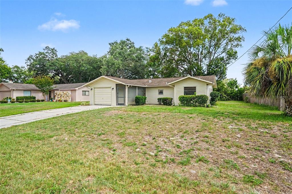 A single-story, light-colored house with a garage and a large, grassy front yard — 9038 BLACKSTONE STREET, SPRING HILL, FL