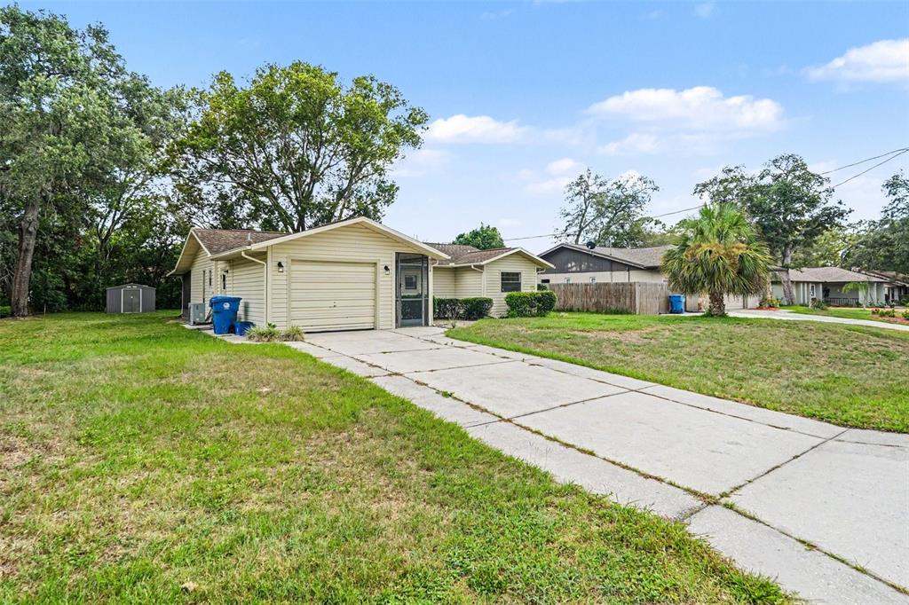 A single-story house with beige siding, a one-car garage, and a concrete driveway — 9038 BLACKSTONE STREET, SPRING HILL, FL
