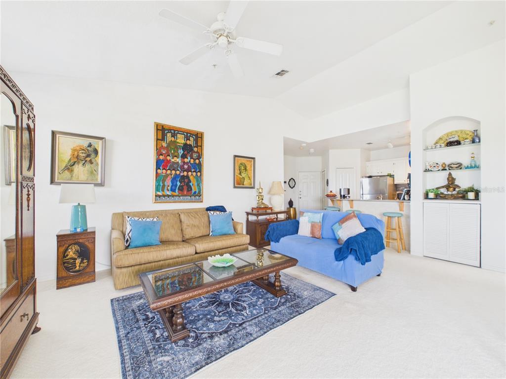 A living room features a tan sofa, a blue sofa, and a glass-topped coffee table — 8816 DUNES COURT UNIT 302, KISSIMMEE, FL