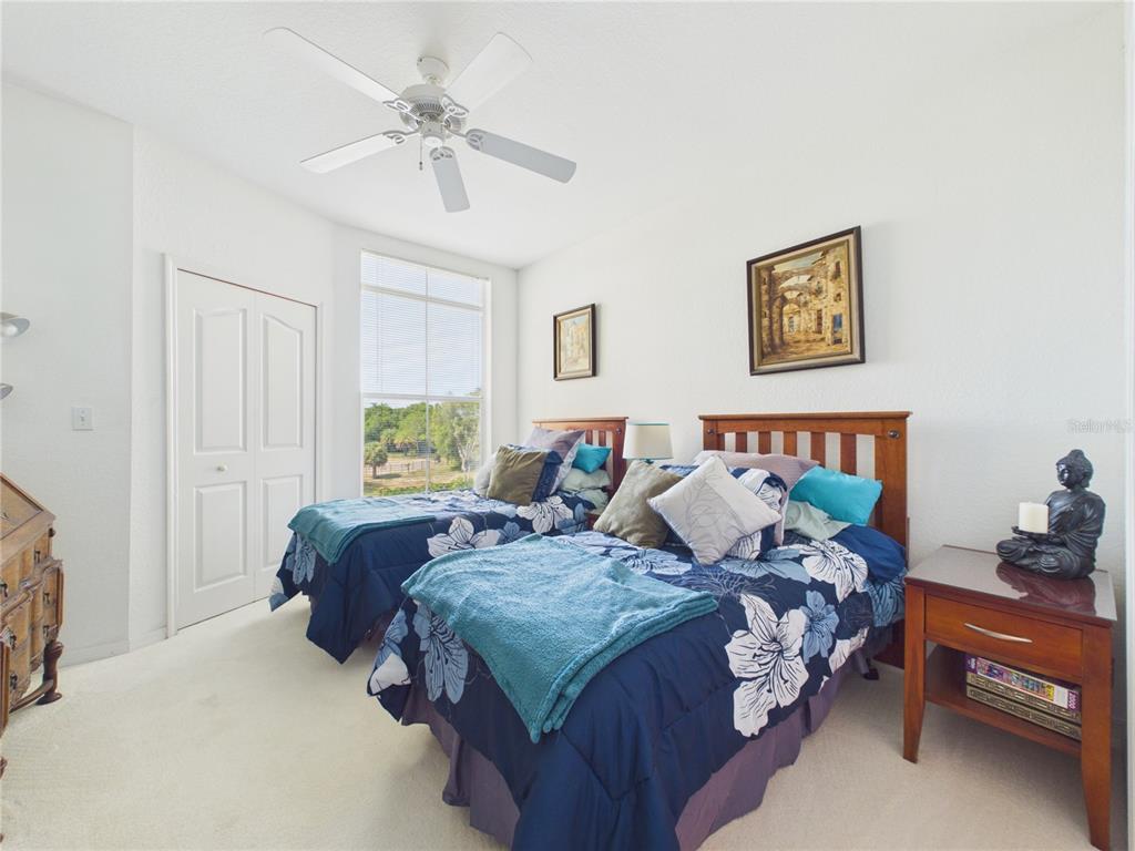 A bedroom features two twin beds with floral bedding, a ceiling fan, and a window — 8816 DUNES COURT UNIT 302, KISSIMMEE, FL