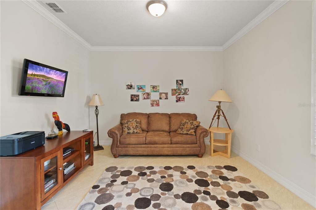 A living room features a brown sofa, a patterned rug, and a television on a stand — 9761 SW 74TH PLACE, OCALA, FL