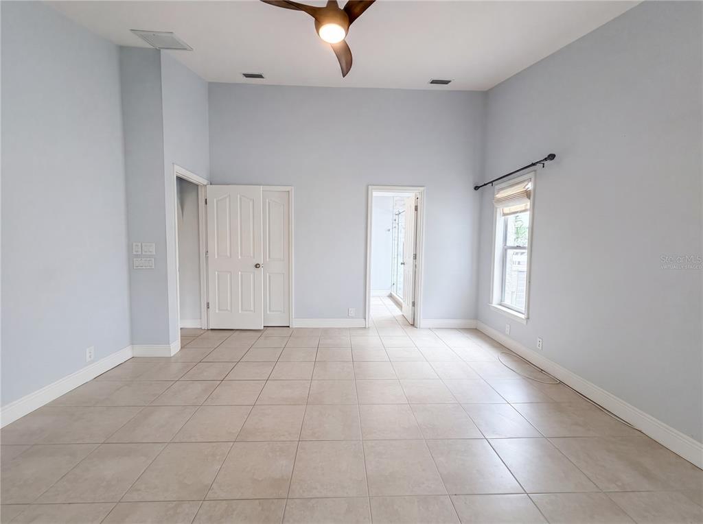 An empty room with light blue walls, tile flooring, a ceiling fan, and two doorways — 4816 61ST AVENUE TERRACE W, BRADENTON, FL