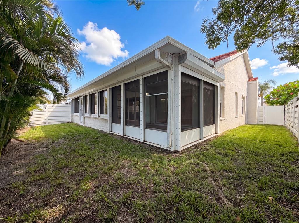 A white house with a screened-in porch sits on a grassy lot with palm trees — 4816 61ST AVENUE TERRACE W, BRADENTON, FL
