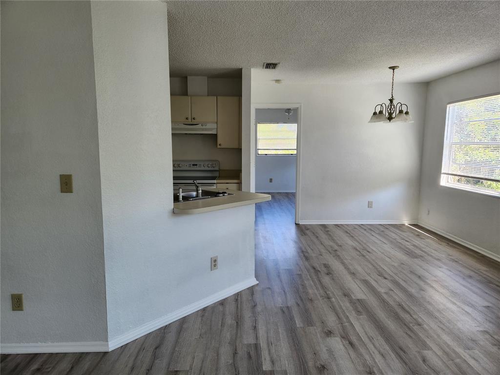 A dining area with wood-look flooring leads to a kitchen with a breakfast bar — 9522 ACE ROAD UNIT B, ENGLEWOOD, FL