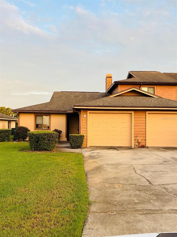 A single-story townhouse with a tan exterior, two garage doors, and a front lawn — 707 CARPENTERS WAY UNIT 8, LAKELAND, FL
