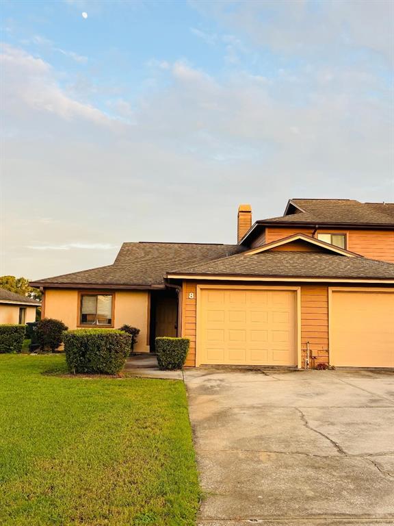 A tan-colored townhouse with a two-car garage and a small front lawn — 707 CARPENTERS WAY UNIT 8, LAKELAND, FL