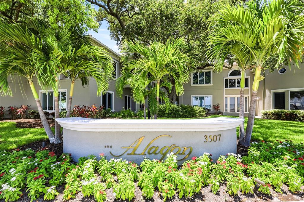 A two-story building exterior with a large tree, green lawn, and white balcony railings — 3507 BAYSHORE BOULEVARD UNIT 102, TAMPA, FL
