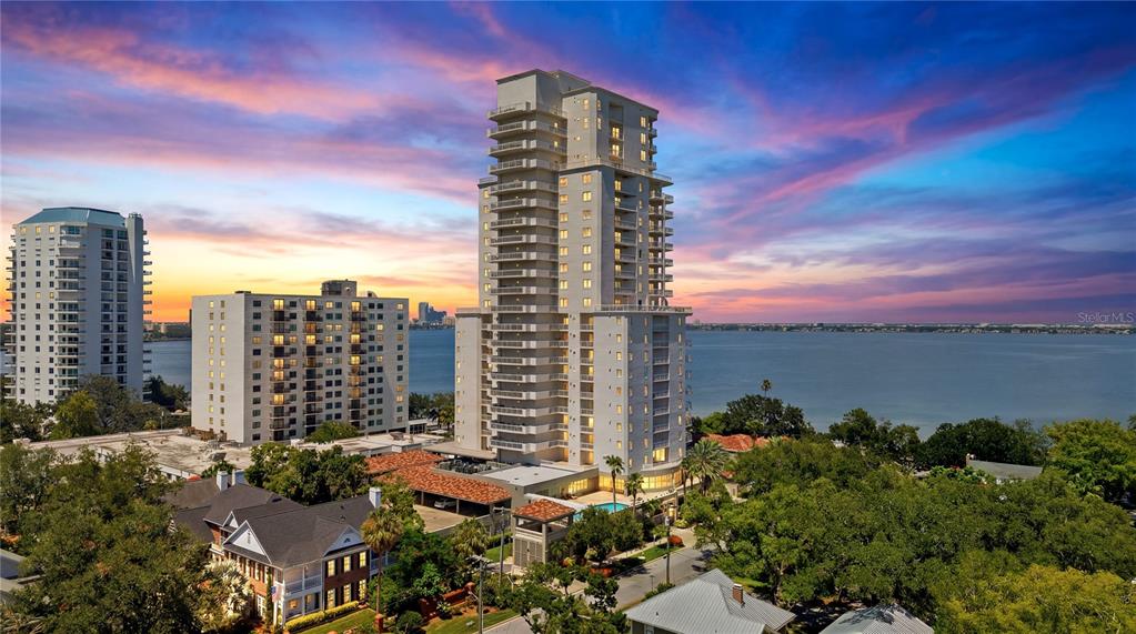 An aerial view shows a tall residential tower and adjacent buildings near a large body — 3507 BAYSHORE BOULEVARD UNIT 102, TAMPA, FL