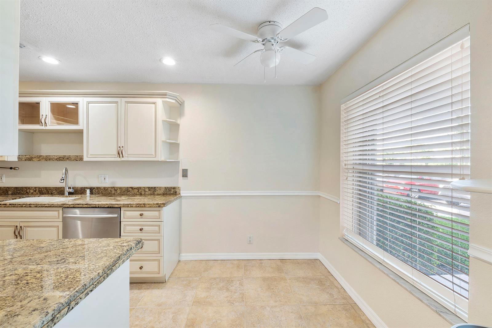 A kitchen with cream cabinets, granite countertops, stainless steel dishwasher, and a large window — 1020 Citrus Way # 101, Delray Beach FL 33445, DELRAY BEACH, FL